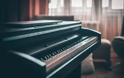 Ciemny fortepian z klawiaturą w zbliżeniu. Zastanawiasz się, ile waży fortepian? Ten instrument jest ciężki, ale piękny.
