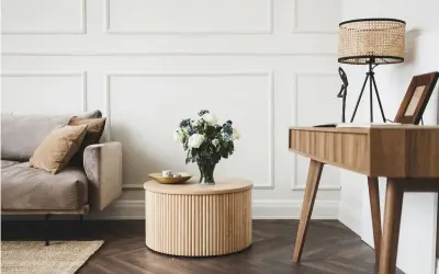 Elegancki salon glamour z dominującym drewnem. Miękka sofa, okrągły stolik i biurko tworzą przytulną przestrzeń.