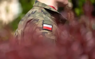 Żołnierz w mundurze z polską flagą. W tle zamazane czerwone liście i zieleń. Choroby dyskwalifikujące ze służby wojskowej mogą wpłynąć na możliwość noszenia takiego munduru.