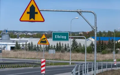 Znaki drogowe: pierwszeństwo przejazdu, przejazd kolejowy, nazwa miejscowości Elbląg.