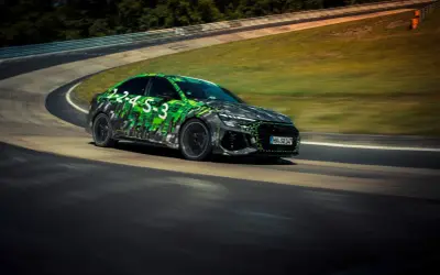 Rs3 Audi w zielono-czarnej kamuflażowej okleinie pędzi po torze wyścigowym.