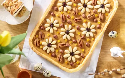 Wielkanocny mazurek ciasto ozdobiony kwiatami z migdałów, orzechami i kandyzowanymi owocami.