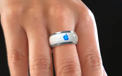 Bague connectée Apple, blanche avec logo bleu lumineux, portée au doigt.