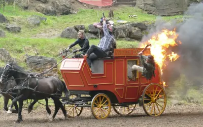 Ein Wagen brennt bei einer Karl May Inszenierung in Elspe. Zwei Männer kämpfen, einer fällt aus dem brennenden Wagen.