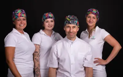Zespół gabinetu stomatologicznego w Łodzi w kolorowych czepkach i białych uniformach.