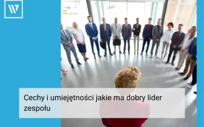 Grupa ludzi w garniturach stoi w kręgu, słuchając swojego **team leadera**.