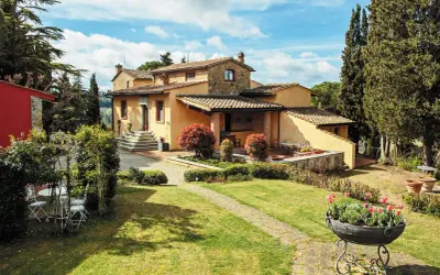 Un perfetto weekend in Toscana: villa con giardino fiorito, cipressi e un cielo azzurro con nuvole bianche.