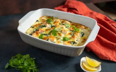 Herzhafte Lachs Spinat Lasagne, goldbraun überbacken, garniert mit frischer Petersilie. Dazu Zitronenspalten.