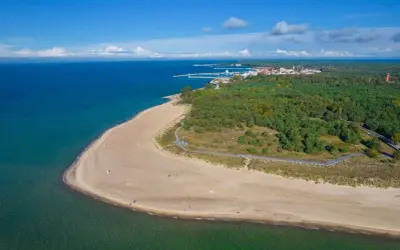 Spokojna plaża i las na Helu poza sezonem. W oddali widać miasteczko i port.