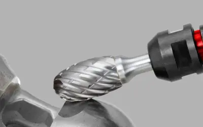 Metalowy frez z nacięciami, zamocowany w uchwycie, zbliża się do metalowego elementu.