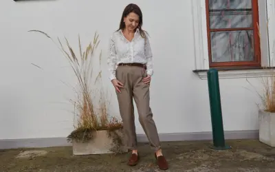 Elegancki ubiór na rozmowę o pracę: biała koszula z ażurowymi detalami, brązowe spodnie z wysokim stanem i mokasyny.