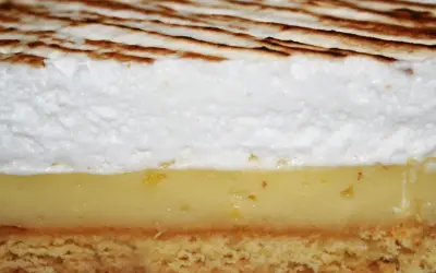 Tranche de tarte au citron avec une généreuse couche de meringue italienne dorée.