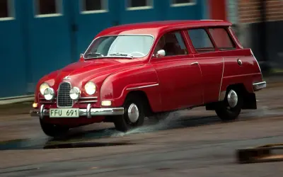 Röd Saab 2-takt kombi kör genom vattenpölar.