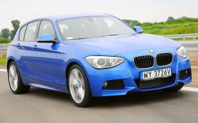 Niebieskie BMW 116i pędzi po drodze, ukazując swoje sportowe linie i dynamiczny charakter.