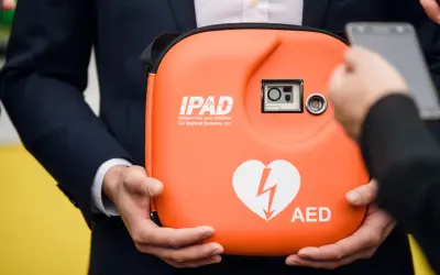 Pomarańczowy AED w etui, z sercem i błyskawicą. Zastanawiasz się, ile kosztuje AED?