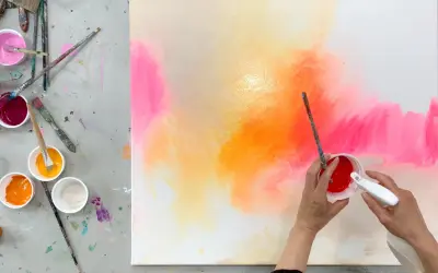 Bunte Farben auf einer Leinwand, bereit zum leinwand bemalen mit kindern. Pinsel und Becher mit Farbe liegen bereit.