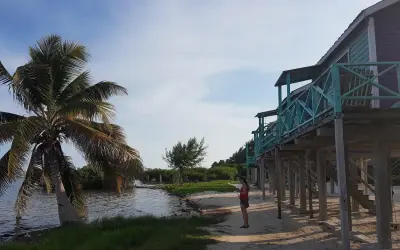 Kobieta na plaży, palmy i domki na palach. Idealne miejsce na belize wakacje.