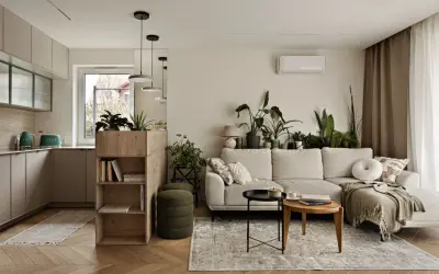 Jasna kuchnia z salonem, z zielonymi akcentami i mnóstwem roślin. Sofa w salonie, stoliki kawowe i regał z książkami.