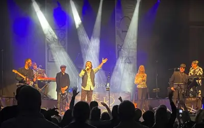 Medlemmar av Dr Hook uppträder på scenen under en konsert, med sångaren i centrum som sjunger i mikrofonen.