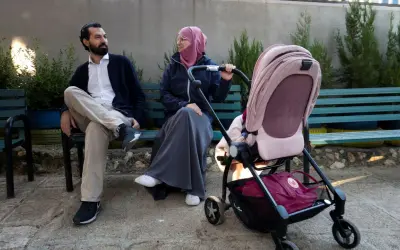 En man och en kvinna, som representerar muslimer i Sverige, sitter på en bänk med en barnvagn.