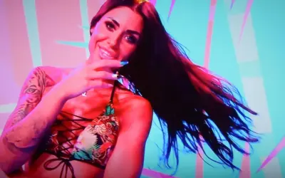 Stella z Love Island w kolorowym bikini, z tatuażem tygrysa na ramieniu, uśmiecha się do kamery.