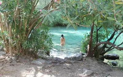 Una mujer se baña en la cueva del gato, un oasis de aguas cristalinas rodeado de vegetación exuberante.