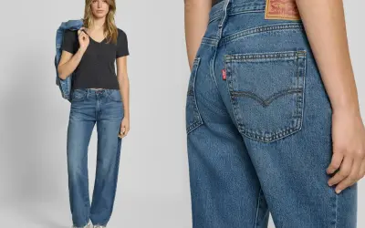 Modelka w jeansach Levi's i czarnej bluzce, z kurtką dżinsową na ramieniu. Detal zbliżenia na tył spodni z charakterystyczną czerwoną metką.