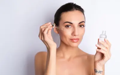 Kobieta aplikuje na twarz serum z peptydami. Skóra wygląda na nawilżoną i promienną.