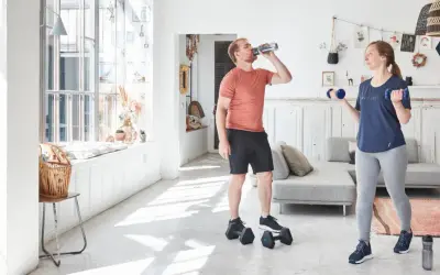 Un homme boit de l'eau pendant que sa compagne fait des exercices avec des haltères, développant ses muscles du bras.