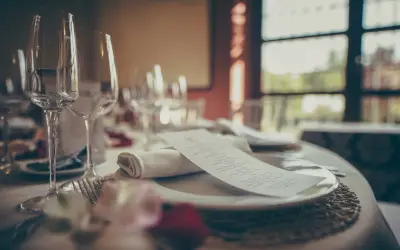 Mesa elegante con copas, cubiertos y menú. ¿Cuántas estrellas Michelin se pueden tener en una cena así?