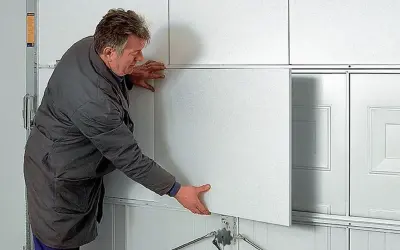Mężczyzna montuje panel do ocieplenia bramy garażowej.