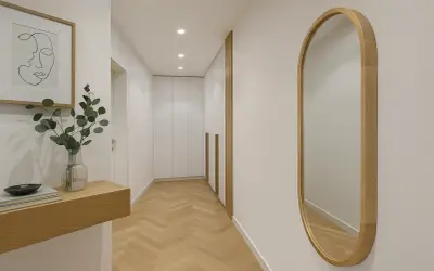 Eleganckie lustro owalne w drewnianej ramie odbija światło w nowoczesnym korytarzu z parkietem w jodełkę.