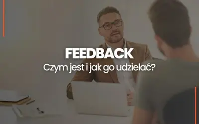Dwóch mężczyzn przy biurku, jeden z nich udziela feedbacku. Czym jest feedback i jak go udzielać?