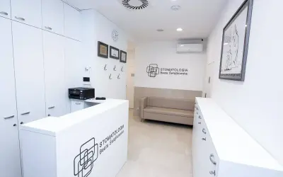 Nowoczesne wnętrze recepcji stomatologicznej z białym lady, kanapą i logo kliniki.
