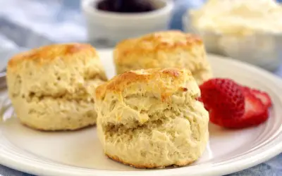 Tre fluffiga scones, ett perfekt scones grundrecept, serveras med jordgubbar och grädde.