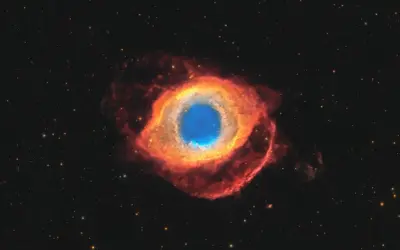 Helixnebulosan, ett kosmiskt öga av gas och stoft, lyser i rött och blått mot en stjärnbeströdd rymd.