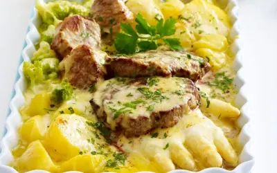 Saftiges Schweinefilet mit Spargel, Kartoffeln und Brokkoli in cremiger Käsesauce, garniert mit Petersilie. Ein köstliches Gericht!