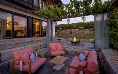 Gemütliche Lounge-Möbel und ein Feuerkorb laden zum Entspannen ein. Die Weinreben über der Pergola und Lichterketten schaffen eine romantische Atmosphäre, perfekt, um die Terrasse zu dekorieren.