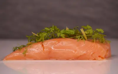 Zartes Lachsfilet, sous vide gegart, mit frischen Kräutern und Zitronenzesten garniert.