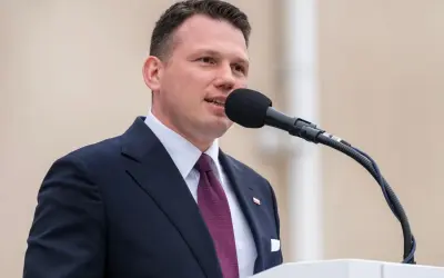 Sławomir Mentzen w garniturze przemawia do mikrofonu. Jego majątek budzi zainteresowanie.