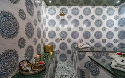 Ett vackert hammam i Marrakech med traditionella mönster på väggarna och golvet. En gyllene skål och skönhetsprodukter står redo för en avkopplande upplevelse.
