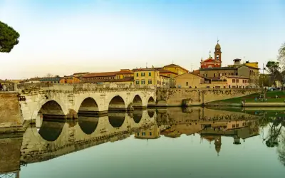 Ponte di Tiberio a Rimini, un luogo che evoca la magia di Fellini, con le sue arcate che si specchiano nell'acqua calma.