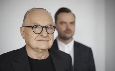 Starszy pan w okularach, Andrzej Dużyński, wiek świadczy o doświadczeniu. Obok niego młodszy mężczyzna w garniturze.