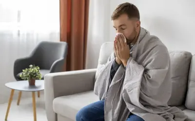 Mężczyzna okryty kocem, z chusteczką przy nosie, może sugerować objawy choroby, ale czasem to tylko próba zwrócenia na siebie uwagi, jak w przypadku zespołu Munchausena.