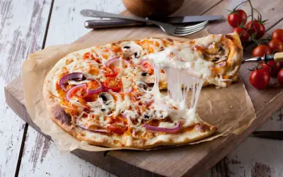 Rozciągający się ser z pizzy 32 cm z pomidorkami i cebulą. Zastanawiasz się, ile kcal ma pizza 32 cm?