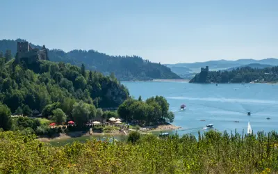 Zamek w Pcimiu Dolnym góruje nad jeziorem, po którym pływają łodzie. W oddali widać zaporę.