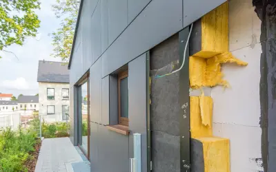 Isolation extérieur : vue rapprochée d'une façade en cours de construction, montrant l'isolant jaune et le revêtement gris. Le prix de cette isolation est un facteur clé pour les propriétaires.