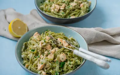 Zwei Schüsseln cremiger Tagliatelle al salmone, garniert mit Petersilie, daneben eine Zitronenhälfte und ein Küchentuch.