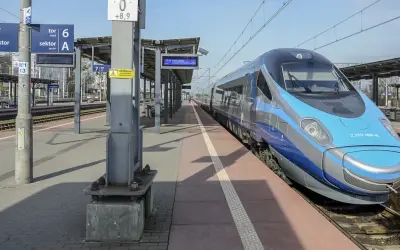 Pendolino na stacji, czy jedzie do Zakopanego? Pociąg stoi na peronie, w tle tablice informacyjne.