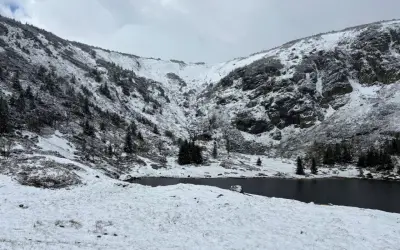 Zimowy krajobraz Karkonoszy z jeziorem i ośnieżonymi zboczami. Śnieg i oblodzenie to przyczyny zamykania szlaków w Karkonoskim Parku Narodowym zimą.
